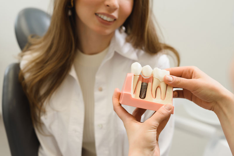 Dental Patient Getting Shown A Dental Implant Model During Her Consultation in Saratoga Springs, UT